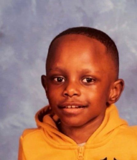 Nazair, age 6, smiling in a yellow hoodie